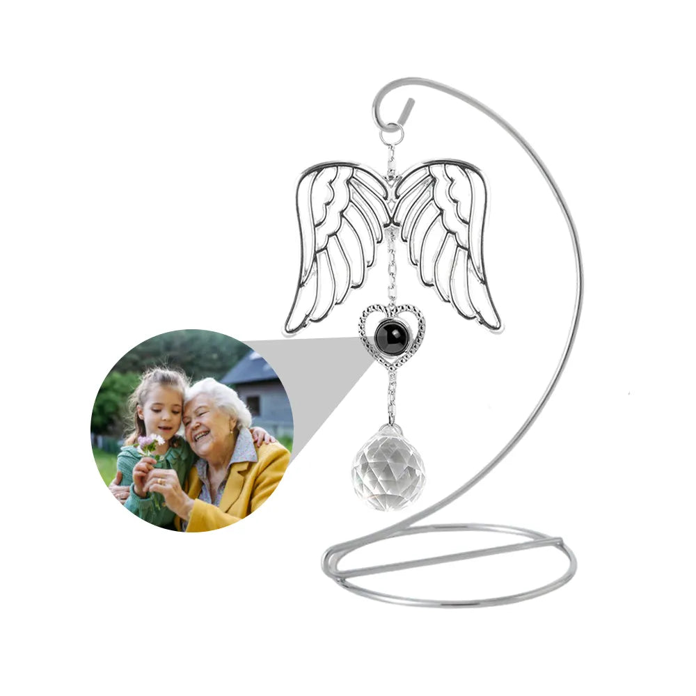 Custom photo angel wing sun catcher with a heart-shaped pendant, which can be customized with photo, hanging on a tabletop stand.